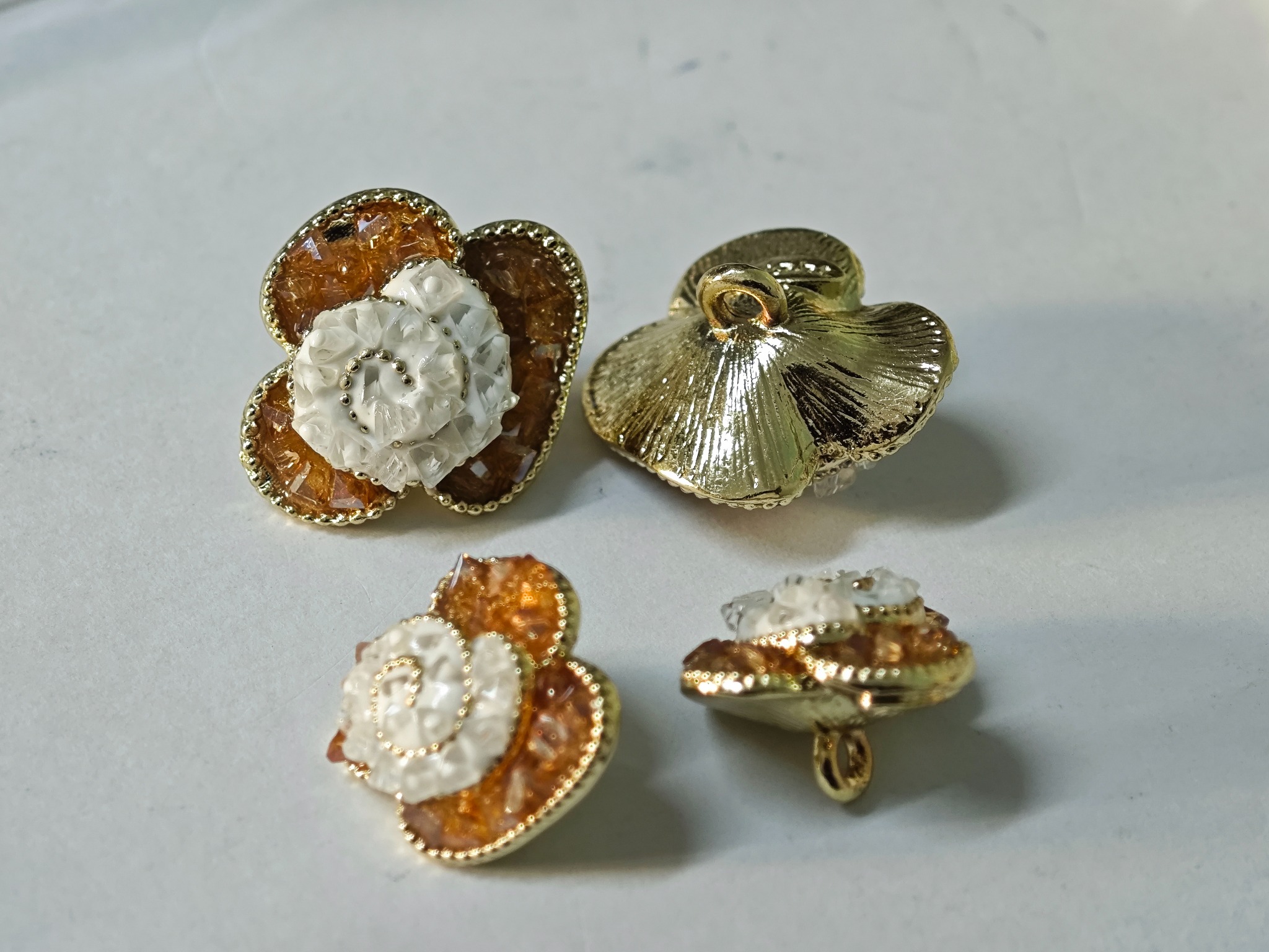 Amber and ivory floral garment buttons shown from the front and reverse