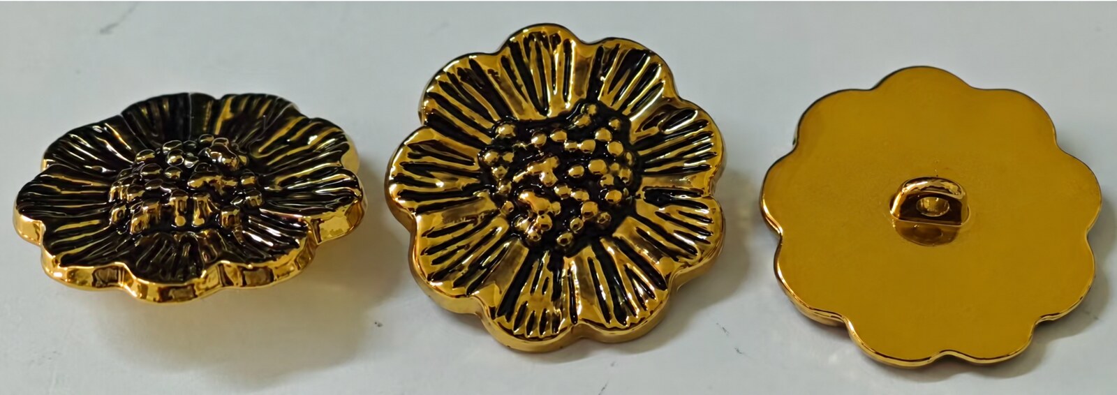 Floral garment button with sculpted relief and an antique black-and-gold finish