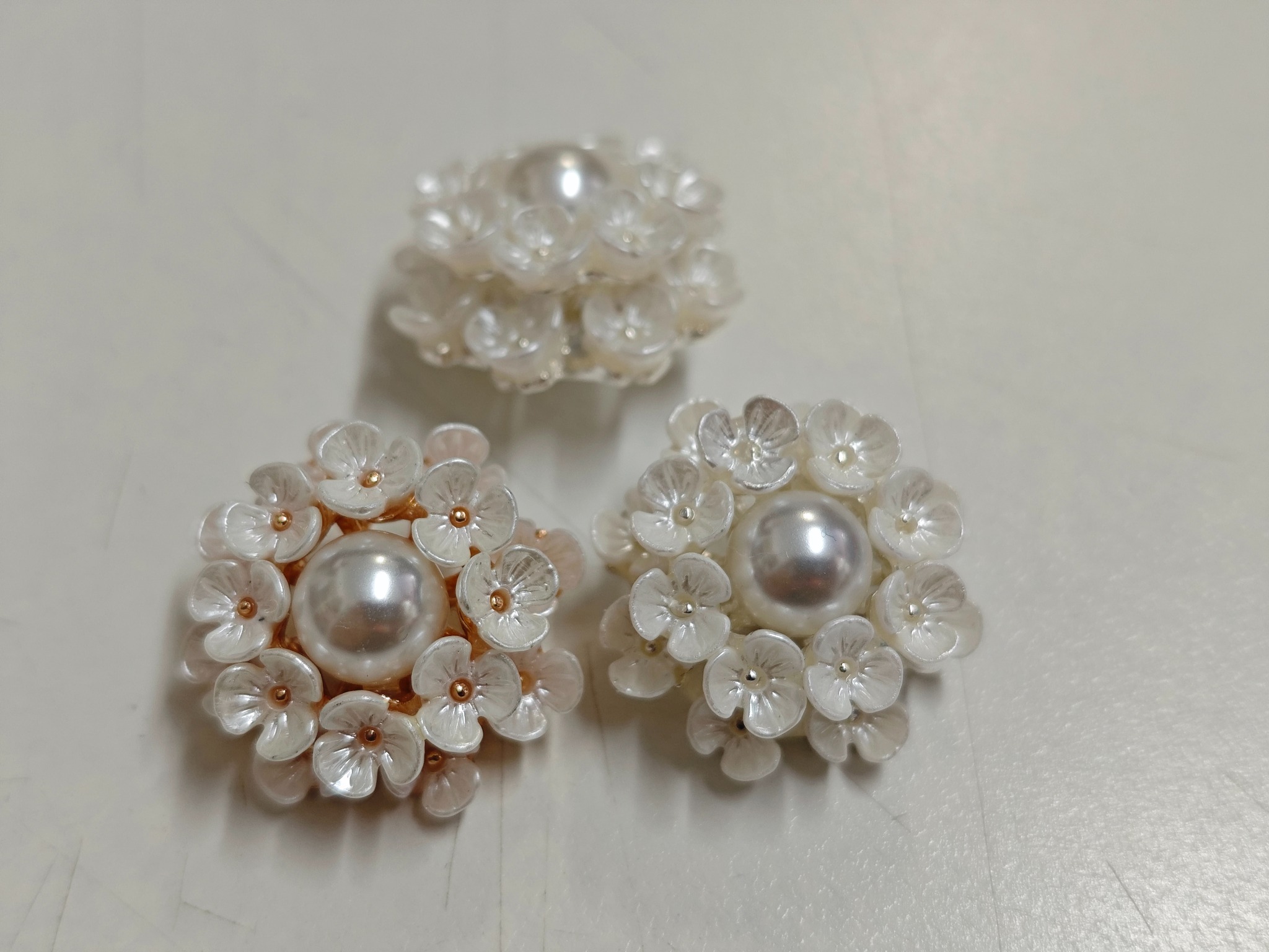 Floral garment buttons with pearl-effect centers and translucent petals