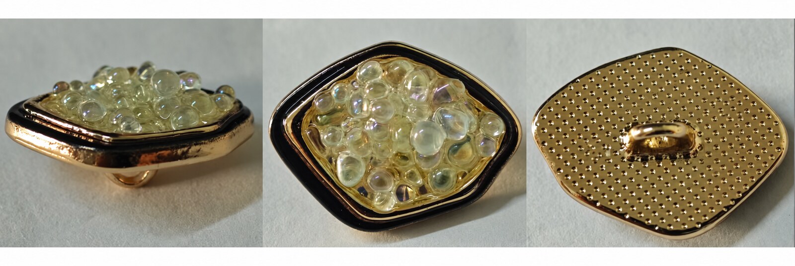 Gold-tone square garment button with a rounded frame and translucent bead-like texture