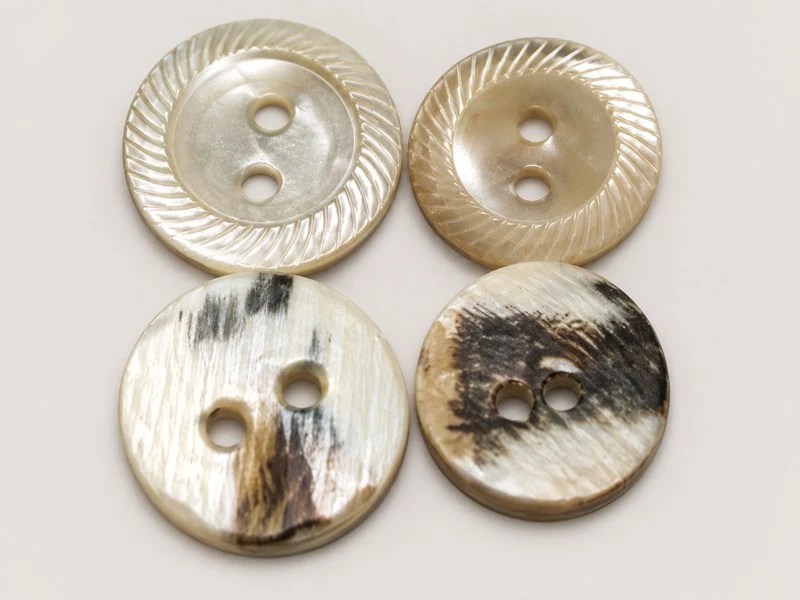 Two-hole shell buttons with a finely fluted rim, shown from the front and back.