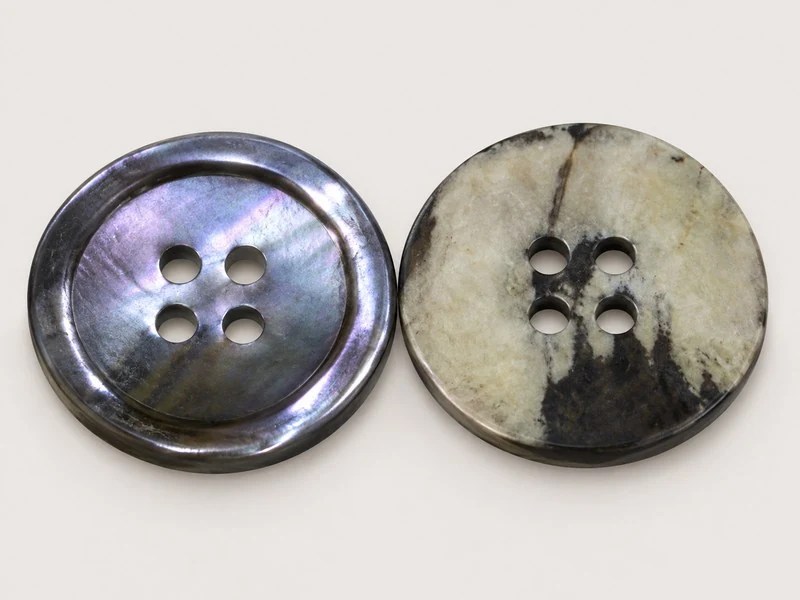 Four-hole Blacklip shell button with an iridescent face and mottled reverse.