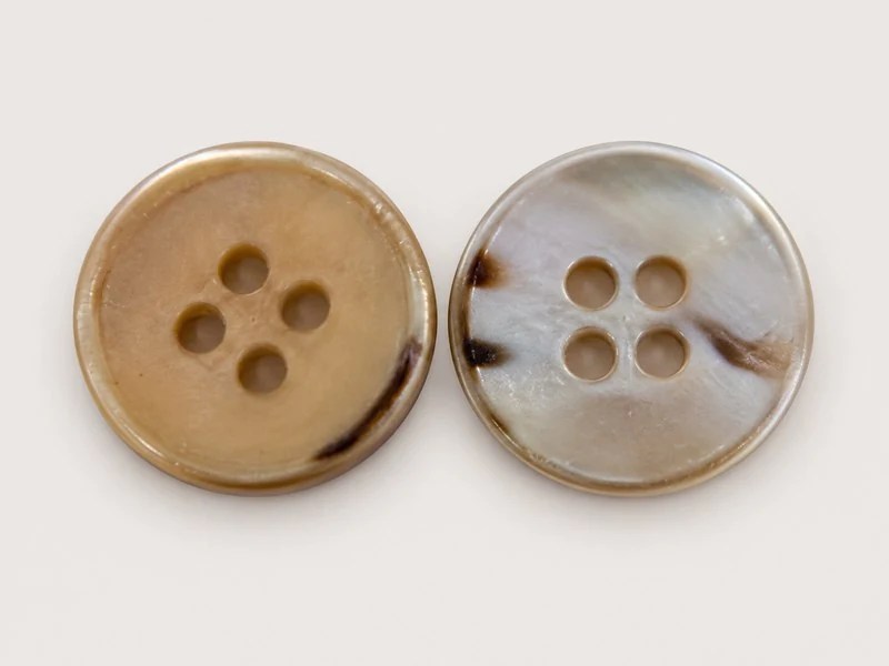 Four-hole shell button with a narrow rim, shown from the front and back.