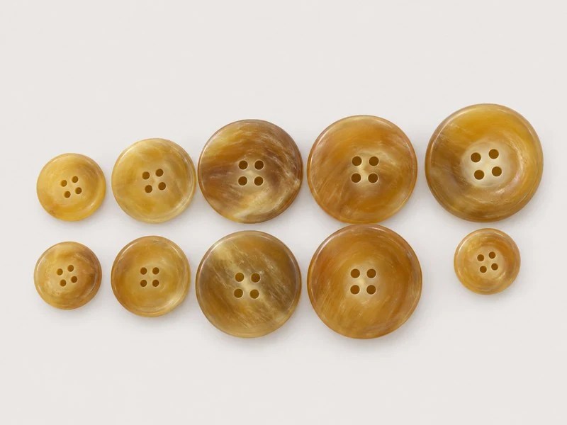 KN2303005 golden-brown horn buttons with broad rims and four sewing holes.